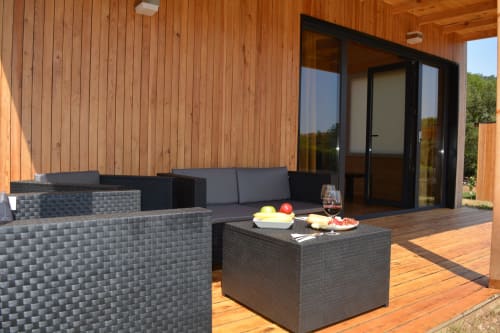 Moderna terraza de Cabañas Compostela con muebles de ratán, tarima de madera y vistas al jardín en Santiago de Compostela