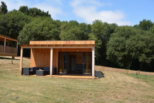 Moderna cabaña de madera con terraza en Cabañas Compostela, rodeada de bosque verde en Santiago de Compostela