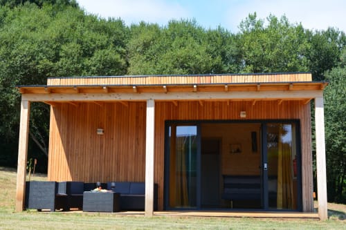 Cabaña moderna de madera con terraza, mobiliario exterior negro y amplios ventanales en Cabañas Compostela, Santiago de Compostela