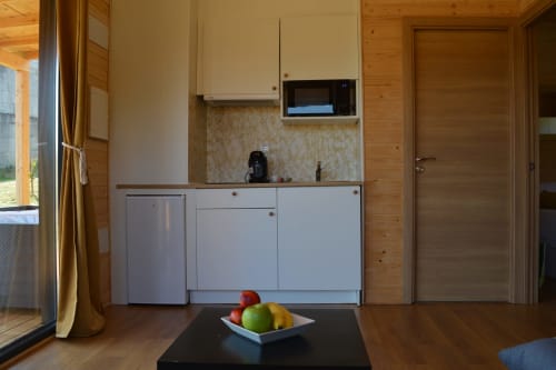 Moderna cocina con armarios blancos, microondas y fregadero en Cabañas Compostela, Santiago de Compostela