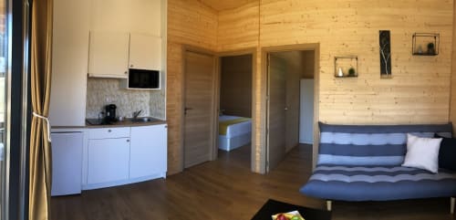 Interior acogedor de cabaña de madera en Cabañas Compostela con cocina, sala de estar, dormitorio y sofá a rayas en Santiago de