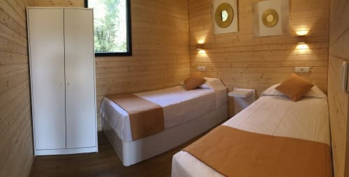 Habitación con dos camas de madera, armario e iluminación ambiental en Cabañas Compostela, Santiago de Compostela