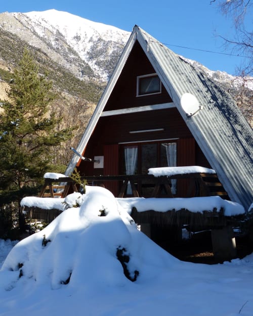 Chalet A-frame enneigé avec vue montagne aux Chalets Cocody, Jausiers, bois foncé et balcon