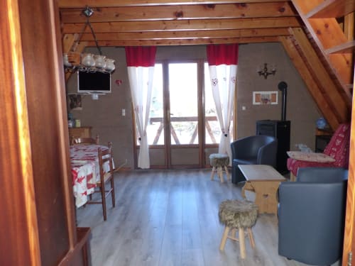Intérieur de chalet classique à Jausiers avec poutres apparentes, salle à manger, salon, télévision et balcon vue montagne