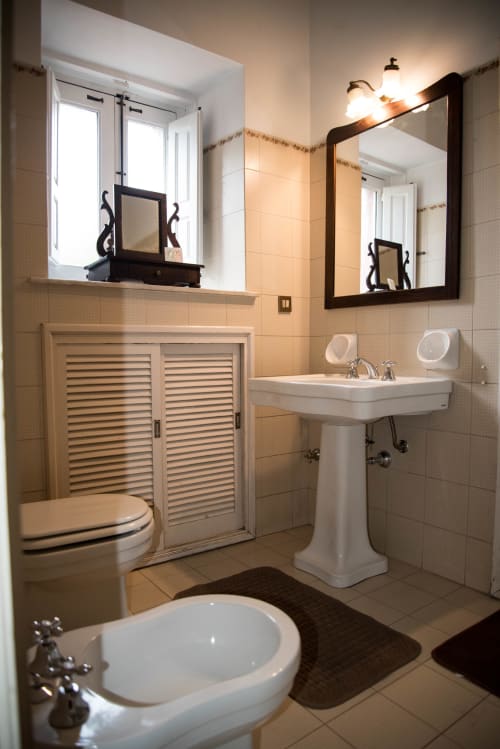 Bagno luminoso della B&B Valle Allegra con lavabo su colonna, wc, specchi e piastrelle beige