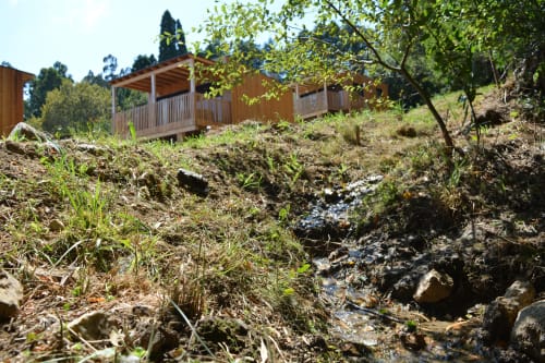 Cabaña de madera con terraza con vistas a arroyo en la ladera de Cabañas Compostela, Santiago de Compostela