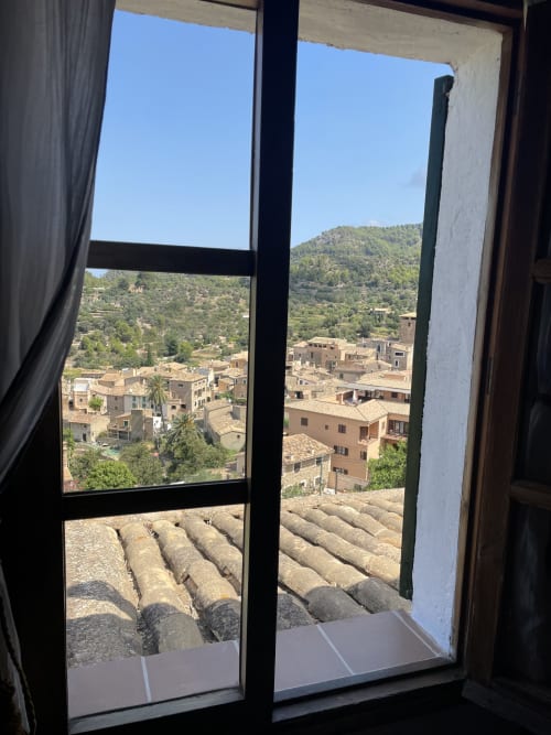 Vista desde la habitación Tramuntana del Petit Hotel Sa Plana, Estellencs, con tejados de terracota y montañas boscosas