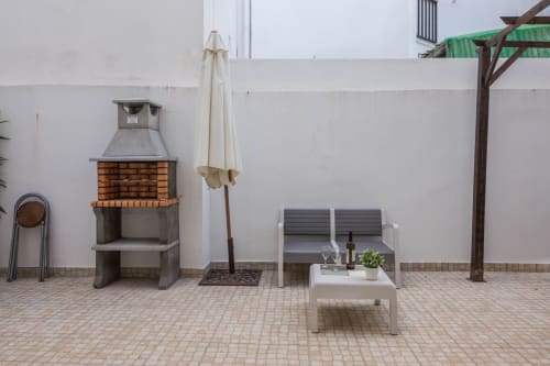 Pátio exterior na Armação Beach Residences com lareira de tijolos, área de estar e guarda-sol em Armação de Pêra
