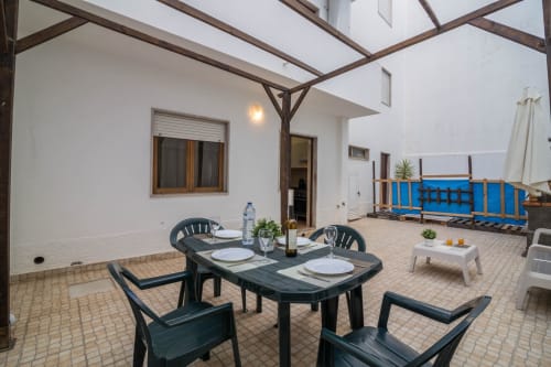 Área de refeições na varanda das Armação Beach Residences com mesa escura, cadeiras, pérgola e vista para a piscina em Armação de Pêra