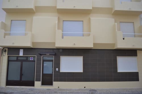 Fachada exterior do Armação Beach Residences com vitrine creme e escura, janelas com venezianas e unidades residenciais acima
