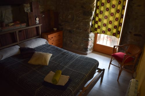 Acogedora habitación en La Calma De Bellver con camas gemelas, sillón amarillo y vistas a las montañas desde la ventana