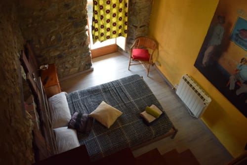 Acogedora habitación de albergue en La Calma De Bellver con cama, paredes amarillas y vistas a la montaña en Bellver de la Cerdanya