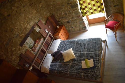 Acogedora habitación compartida en La Calma De Bellver con cama estampada, muebles de madera y ventana con vistas a la montaña