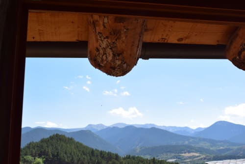 Vista del valle de montaña desde la habitación del hostal La Calma De Bellver con vigas de madera enmarando los picos de los Pirineos en Bellver de la Cerdanya