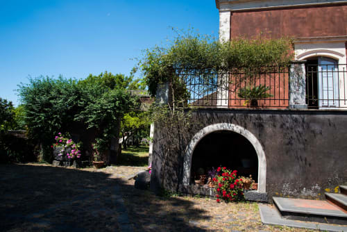 Corte del B&B Valle Allegra con edificio in terracotta, piante fiorite e ingresso ad arco a Gravina di Catania