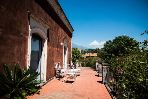Terrazza del B&B Valle Allegra a Gravina di Catania con pavimento in cotto, arredamento bianco e vista sulle montagne