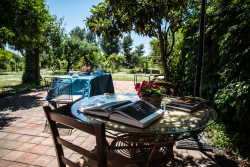 Terrazza giardino con tavolo rotondo, libri e fiori presso B&B Valle Allegra a Gravina di Catania, Italia