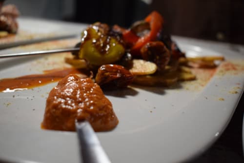 Plato gourmet de entrada en el hostal La Calma De Bellver en Bellver de la Cerdanya con carne sellada, aceitunas y vegetales asados