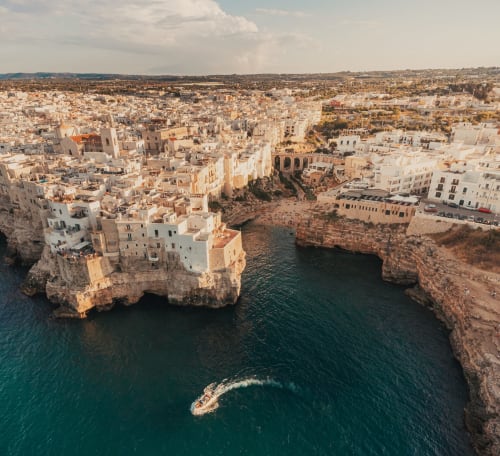 Aerial view of Polignano a Mare's white cliffside buildings overlooking turquoise Adriatic waters