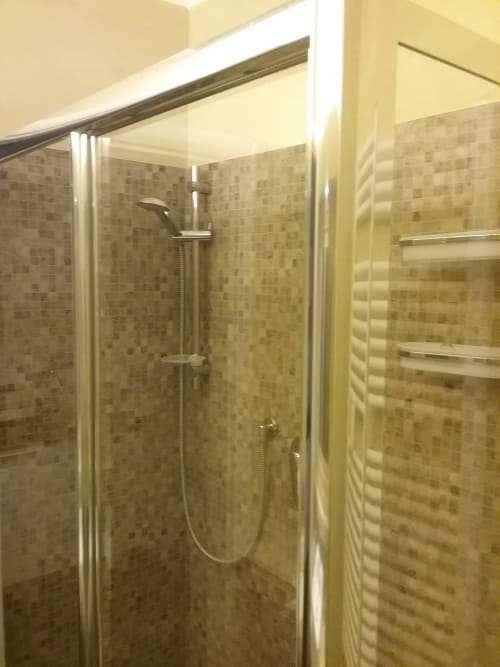 Moderna cabina doccia con porte in vetro e pareti in piastrelle beige nell'appartamento Tommaso di Orso Luxury Apartments, Roma
