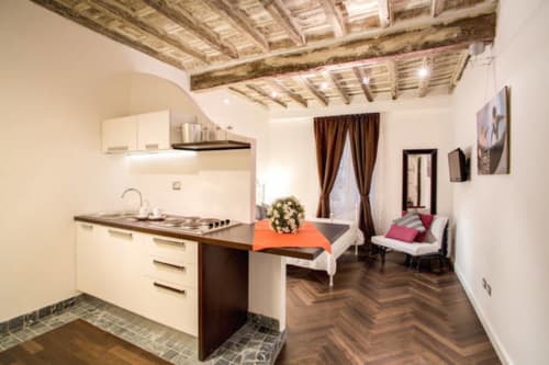Moderno monolocale di lusso presso Orso Luxury Apartments Roma con cucina, letto e soffitto in legno rustico