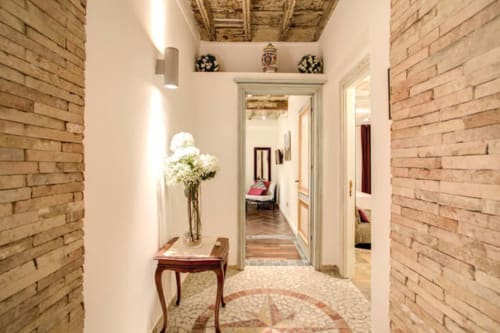 Elegante corridoio presso Orso Luxury Apartments a Roma con muri in laterizio a vista, soffitto bianco, arredamento in legno e aria fresca