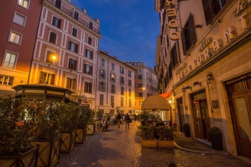 Via romana storica in ciottolato al tramonto con eleganti edifici e cena all'aperto, presso Orso Luxury Apartments