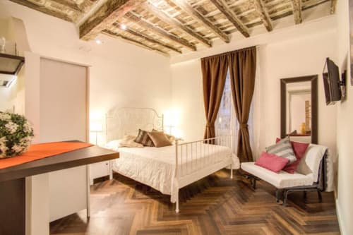 Tommaso apartment bedroom at Orso Luxury Apartments in Rome, featuring white metal bed, herringbone floors, exposed beams