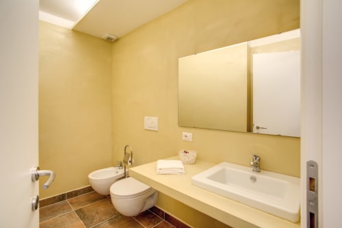 Bernini apartment bathroom at Orso Luxury Apartments Rome with yellow walls, double sink vanity, and bidet