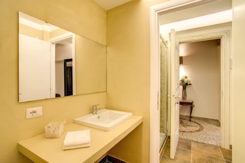 Bernini apartment bathroom at Orso Luxury Apartments Roma with yellow walls, vessel sink, and mirror
