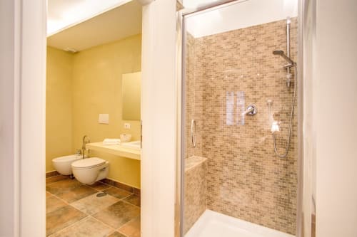 Modern bathroom in Bernini apartment at Orso Luxury Apartments Roma, featuring yellow walls, tiled shower, and contemporary