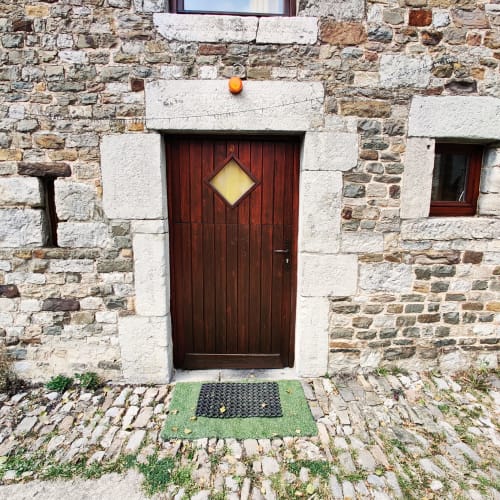 Entrée pittoresque d'une chaumière en pierre avec porte rouge foncé et volet jaune, La Ferme De Werpin, Hotton Belgique