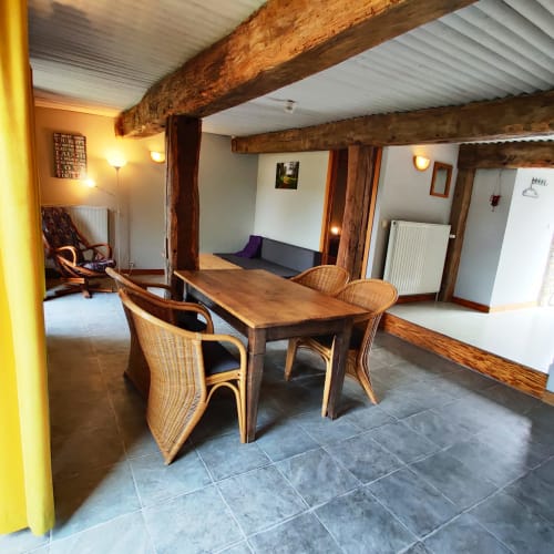 Salle à manger rustique à La Ferme De Werpin avec poutres en bois, chaises en osier et sol en ardoise à Hotton