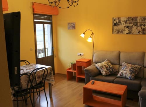 Aconchegante sala de estar em Turismo en Sanabria em Vigo com paredes amarelas, sofá cinza, móveis laranja e madeira