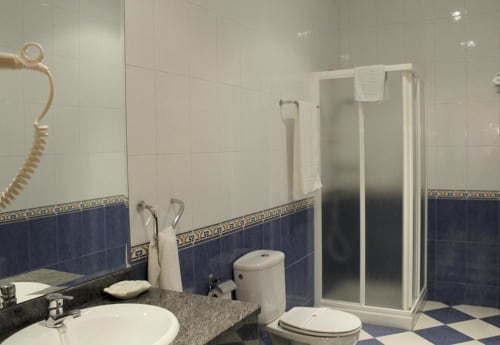 Banheiro moderno do hotel Turismo en Sanabria em Vigo com azulejos brancos, detalhes em azul, box de chuveiro e pia