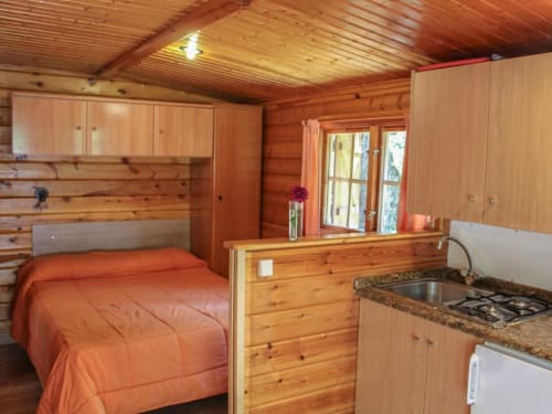 Interior acogedor de cabaña de madera con cama de matrimonio, cocineta y puertas de cristal en Turismo en Sanabria, Zamora