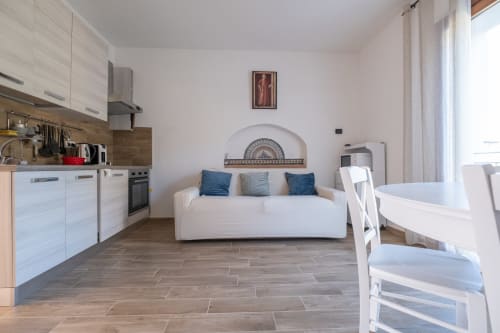 Moderno monolocale presso La Casetta di Pietra B&B a Gavorrano con cucina, divano bianco e pavimenti in legno