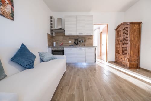 Studio moderno presso La Casetta di Pietra B&B a Gavorrano con cucina bianca, pavimenti in legno e cuscini blu