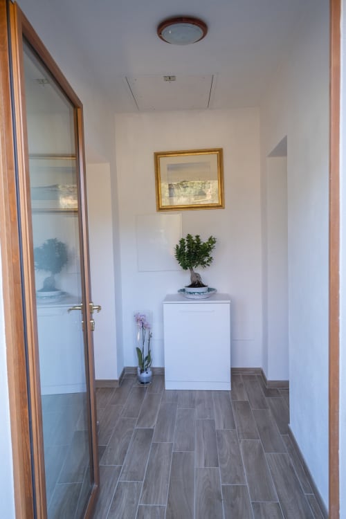 Elegante corridoio della Casetta di Pietra B&B a Gavorrano con pavimentazione a spina di pesce, mobili bianchi e piante decorative