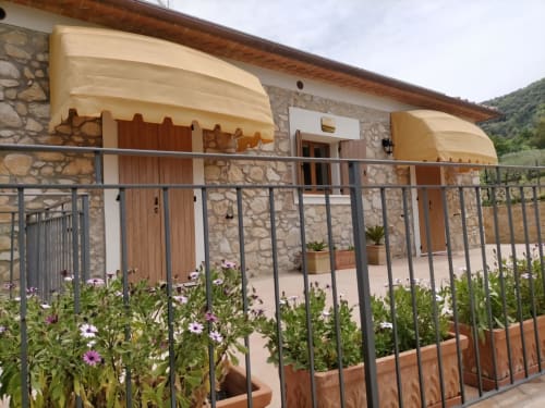 Esterno della Casetta di Pietra B&B con tende gialle, facciata in pietra e terrazza fiorita a Gavorrano