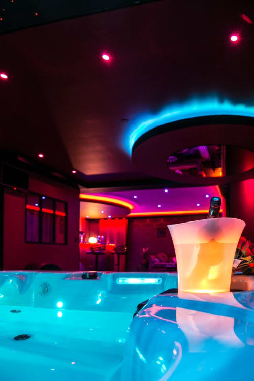 Cocktail luminescent près de la piscine scintillante de l'hôtel-spa L'Insolite à Toulouse, lounge aux néons