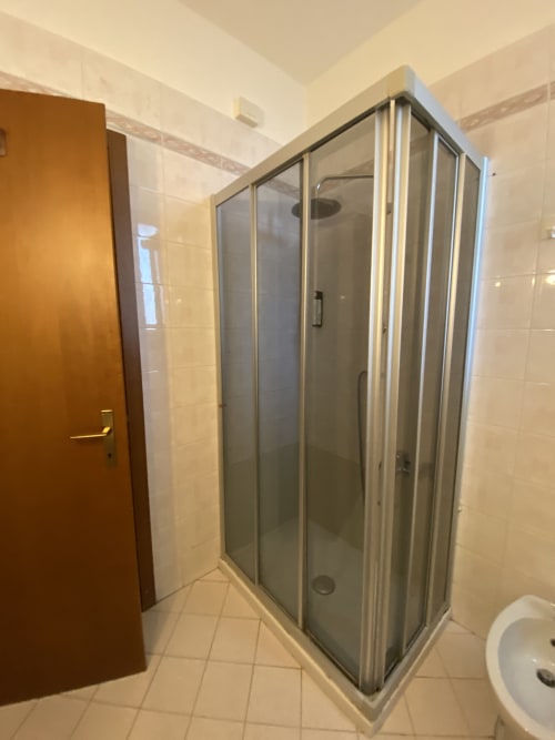 Moderno box doccia nel bagno della Blue Room presso l'Alloggio Le Casette, hotel di Verona, con pareti rivestite in piastrelle e porta marrone