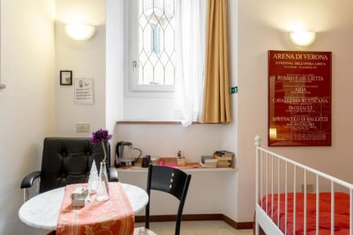 Camera Rossa presso Alloggio Le Casette a Verona con scrivania, tavolo da pranzo e finestra con vista sulla città