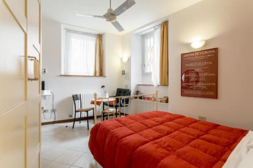 Camera rossa in Alloggio Le Casette a Verona con finestre luminose, scrivania, area di lavoro e vista sulla città
