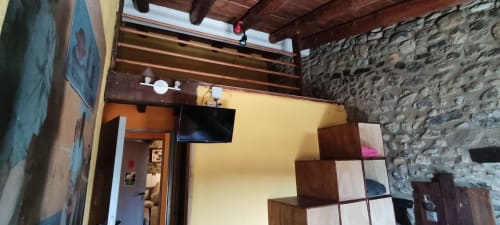 Habitación moderna en el hostel La Calma De Bellver con vigas de madera, paredes de piedra, TV y mobiliario contemporáneo