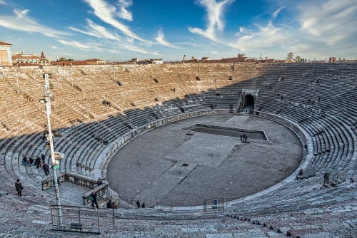 Ancient Roman amphitheater Arena di Verona with stone seating and arena floor under blue sky