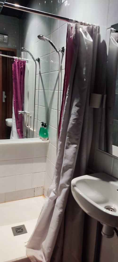 Baño moderno del hostel La Calma De Bellver con ducha, lavabo y toallas púrpura en Bellver de la Cerdanya