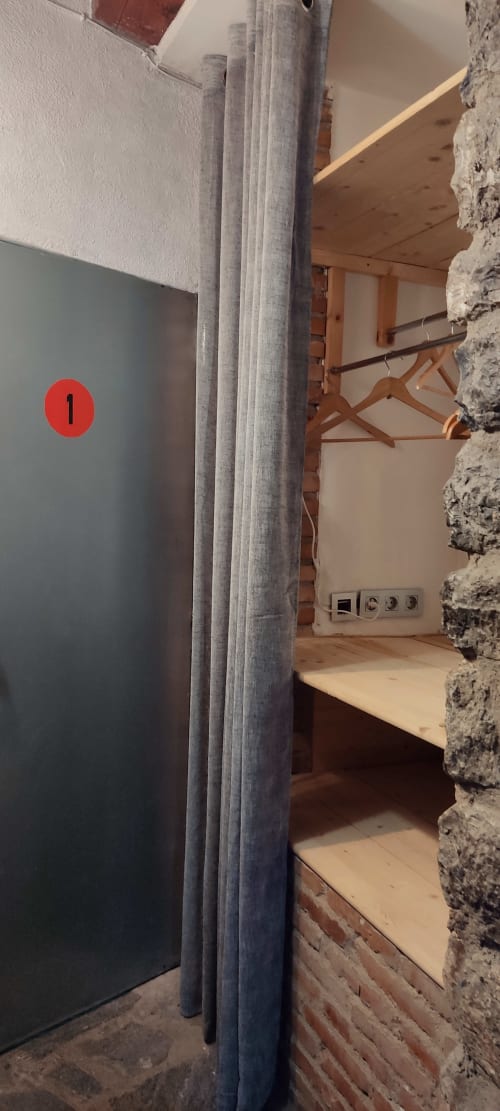 Habitación de hostal en La Calma De Bellver con vigas de madera, aislamiento gris y enchufes eléctricos visibles