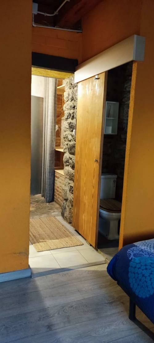 Entrada de habitación en el albergue La Calma De Bellver con puertas de madera, muros de piedra y ambiente de casa de montaña en Bellver de la