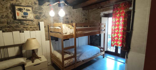 Acogedor cuarto con litera en el albergue La Calma De Bellver en Bellver de la Cerdanya, con paredes de piedra y acceso a balcón